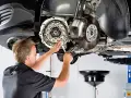 Mechanik pracuje przy skrzyni biegów, gdzie widoczny jest element dwumasy.