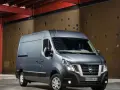 Szary Nissan NV400 stoi przed brązową, perforowaną ścianą w industrialnym wnętrzu.