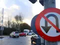 Znak zakazu zawracania na skrzyżowaniu. Samochody stoją w deszczu, czekając na zielone światło.