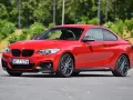 Czerwone BMW f23 coupe z czarnymi dodatkami i felgami stoi na asfalcie.