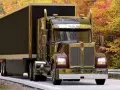 Błyszczący Kenworth W900 z przyczepą jedzie drogą wśród jesiennych drzew.