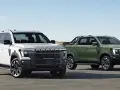 Dwa SsangYong pickup: biały i zielony, stojące na tle plaży i wydm.