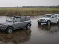 Szary Ford Bronco i biały Jeep SUV stoją w płytkiej wodzie, gotowe na przygodę.