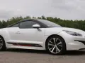 Biały Peugeot RCZ z czarnym dachem i sportowymi akcentami na progu, zaparkowany na tle zielonego lasu.