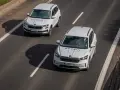 Dwa białe samochody Skoda Auto Szkoła jadą po drodze, gdzie obowiązuje ruch lewostronny.