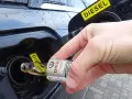 Ręka wlewa dodatek do diesla z małej buteleczki do baku samochodu.