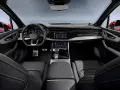 Wnętrze Audi Q7 z ekranami, kierownicą i skórzanymi fotelami.