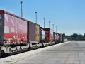 Długi pociąg towarowy z kontenerami, w tym czerwonymi z logo COSCO i żółtymi, czeka na dalszy transport kolejowy.