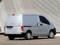 Srebrny Nissan NV200, wszechstronny van, zaparkowany przed nowoczesnym budynkiem.