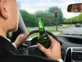 Kierowca z butelką piwa w ręku, jadący na czerwonym świetle. Grozi mu konfiskata samochodu.