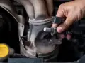 Dłoń trzyma czujnik tlenu, potencjalna przyczyna błędu DTC P0420 w Volkswagenie.