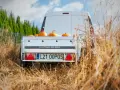 Biała furgonetka z przyczepą pełną dyni, gotowa do transportu. Spedytor czeka na załadunek.