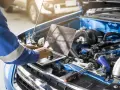 Mechanik w niebieskim kombinezonie wykonuje mapowanie silnika na laptopie, analizując jego pracę.