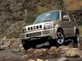 Złoty Suzuki Jimny pokonuje kamienisty strumień. Sprawdź suzuki jimny cena i możliwości terenowe tego kultowego auta.