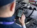 Mechanik sprawdza DTC BMW na smartfonie, analizując dane z silnika.