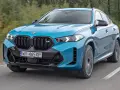 Niebieskie x6 BMW M na drodze, z rozmytym tłem lasu.