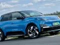 Niebieski Nissan March z czarnym dachem i felgami stoi na poboczu drogi.