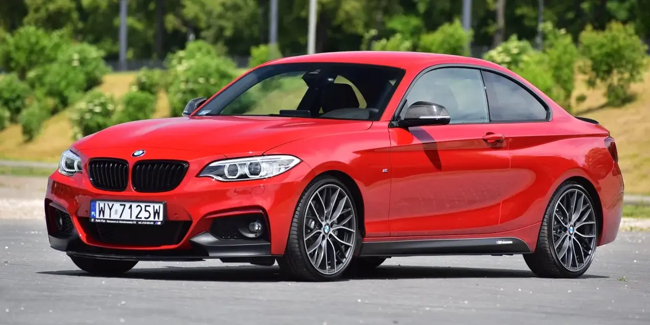 Czerwone BMW f23 coupe z czarnymi dodatkami i felgami stoi na asfalcie.