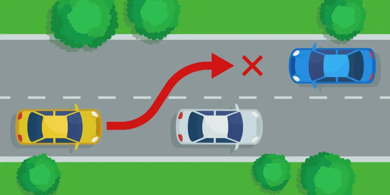 Żółty samochód próbuje niebezpiecznego **wymijania** niebieskiego auta, ignorując białe auto i czerwony znak zakazu.