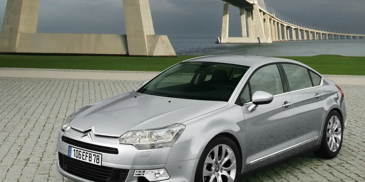 Srebrny Citroen C5 na tle mostu. Wiele osób chwali ten model, a opinie o Citroen C5 są zazwyczaj pozytywne.