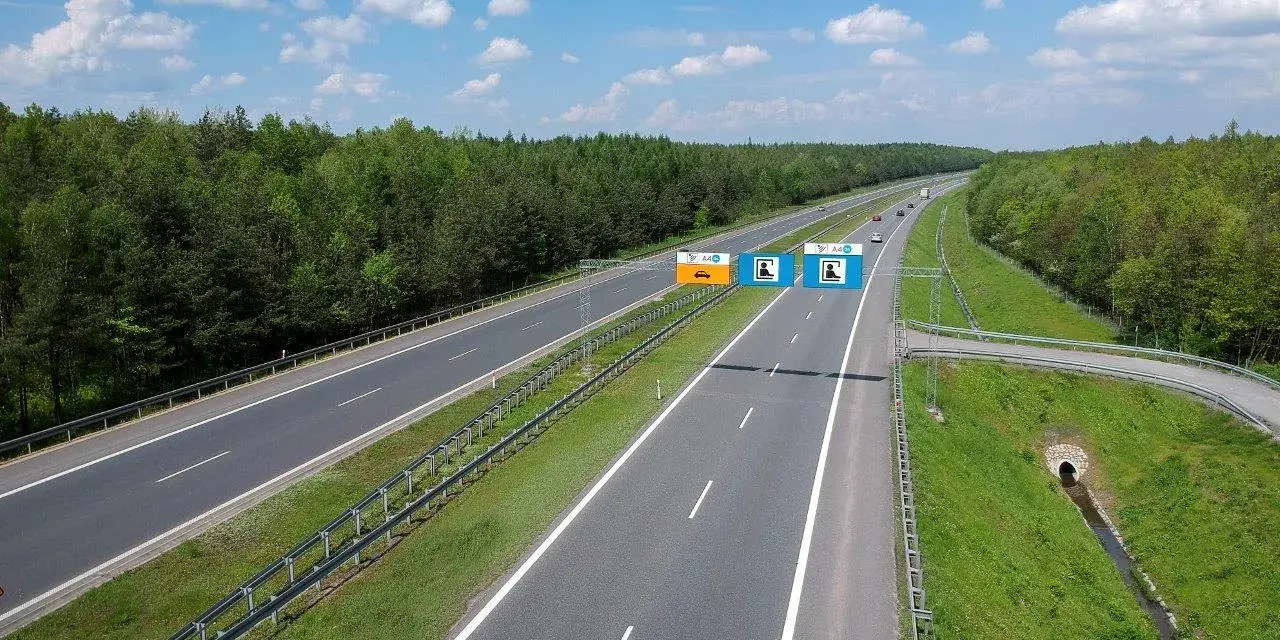 Znaki na autostradzie A4 informują, czy jest ona płatna. Widok na pustą autostradę w słoneczny dzień.