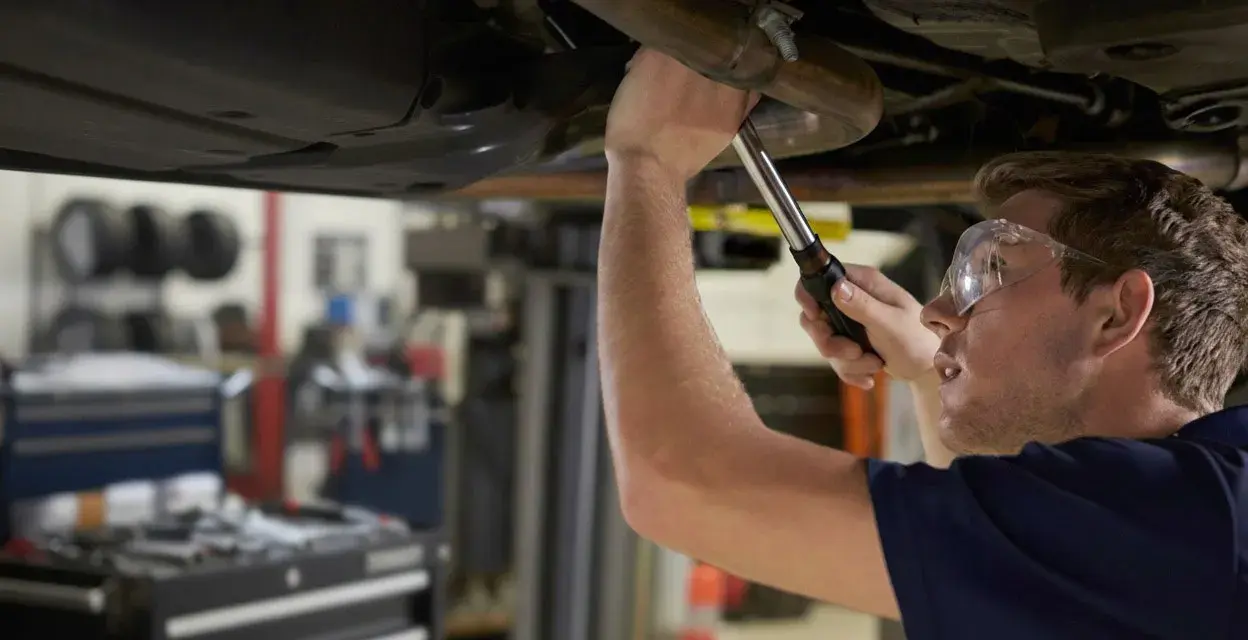 Mechanik naprawia układ wydechowy Renault, być może z powodu błędu DTC P0420.
