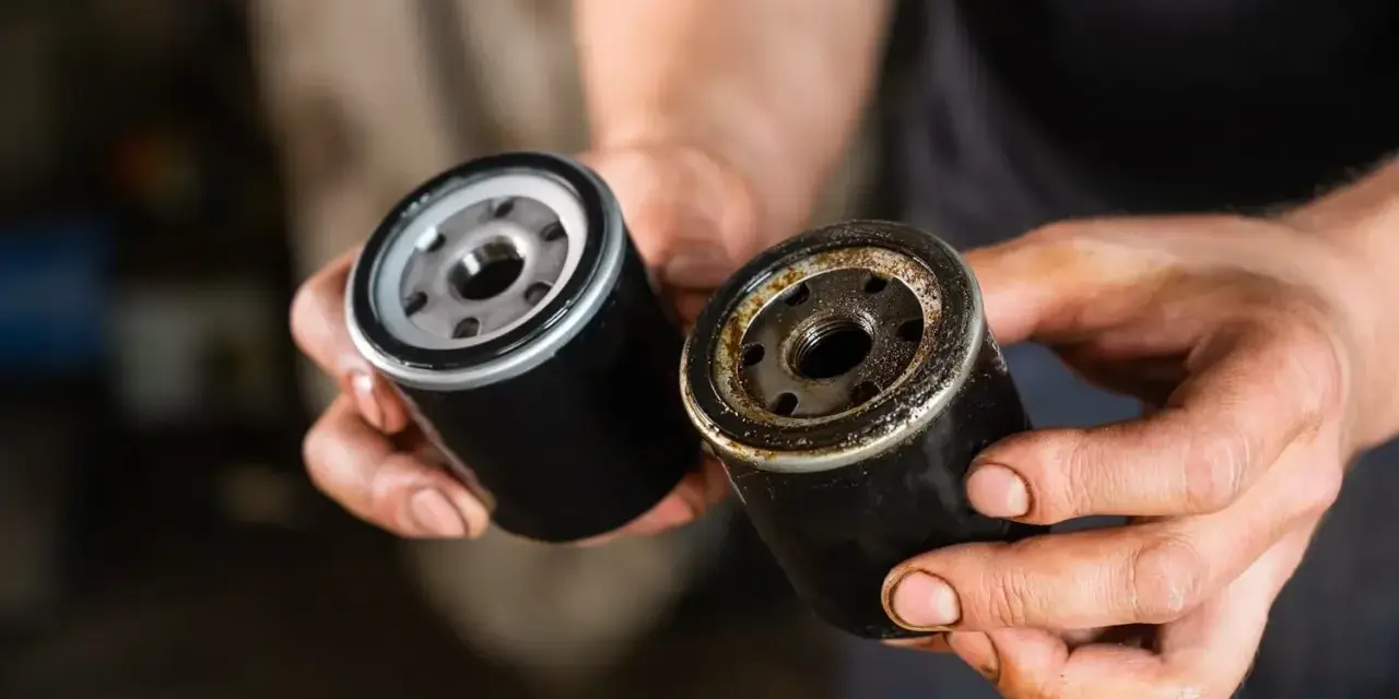 Nowy i zużyty filtr oleju w dłoniach mechanika. Wymiana filtra oleju to kluczowy element dbania o silnik.
