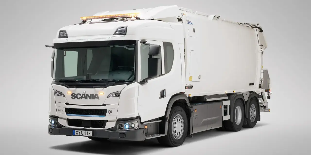 Biała śmieciarka Scania Streamline z niebieskim akcentem na grillu i pomarańczowymi światłami ostrzegawczymi na dachu.