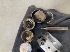 Zużyte popychacze hydrauliczne i inne części silnika pokryte olejem, gotowe do wymiany.
