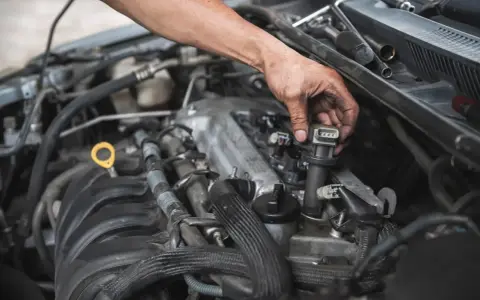 Mechanik wymienia cewkę zapłonową, co może być rozwiązaniem problemów z nierówną pracą silnika.