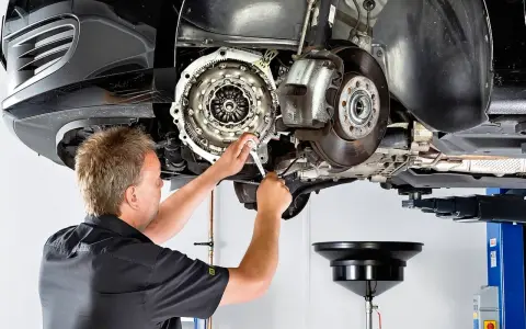 Mechanik pracuje przy skrzyni biegów, gdzie widoczny jest element dwumasy.