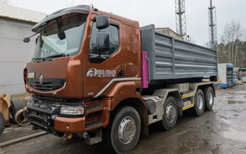Brązowy Renault Kerax z naczepą wywrotką, gotowy do pracy na placu budowy.