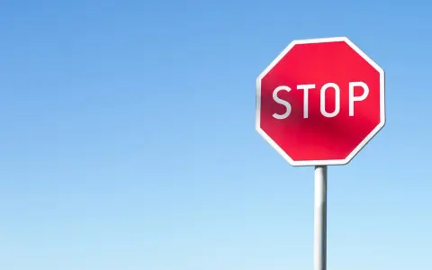 Czerwony znak STOP na tle błękitnego nieba. Uważaj, by nie dostać mandatu za stop!