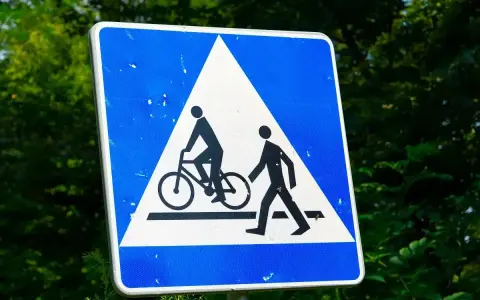Znak ostrzegawczy: przejazd rowerowy i przejście dla pieszych. Czy rowerzysta ma pierwszeństwo na przejeździe rowerowym? Tak, ten znak informuje o tym.