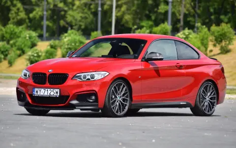 Czerwone BMW f23 coupe z czarnymi dodatkami i felgami stoi na asfalcie.