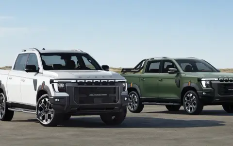 Dwa SsangYong pickup: biały i zielony, stojące na tle plaży i wydm.