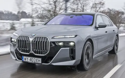 Szary BMW Serii 7 w ruchu, z widocznym grillem i reflektorami. Sprawdź aktualną bmw 7 cena.