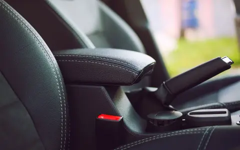 Wnętrze samochodu: czarna skórzana tapicerka, podłokietnik, hamulec ręczny i przycisk auto hold.