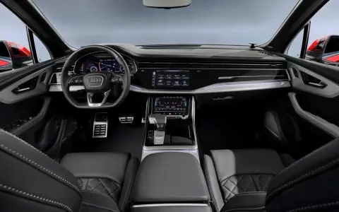 Wnętrze Audi Q7 z ekranami, kierownicą i skórzanymi fotelami.