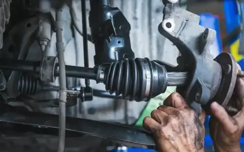 Mechanik wymienia przegub w samochodzie. Dowiedz się, ile kosztuje wymiana przegubu i jakie są objawy jego zużycia.