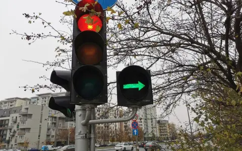 Sygnalizacja świetlna: czerwone światło na głównym słupku, a obok zielona strzałka warunkowa w prawo.