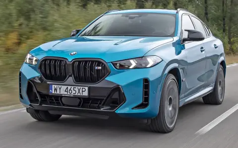 Niebieskie x6 BMW M na drodze, z rozmytym tłem lasu.