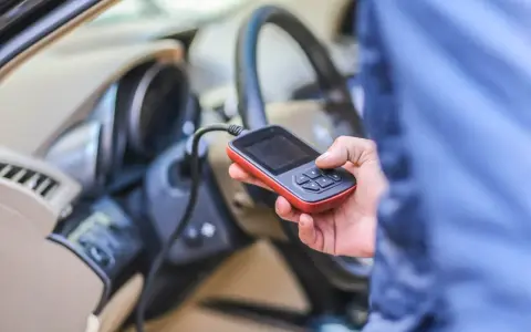 Diagnostyka Renault, być może błąd DTC B1267. Ręka trzyma urządzenie diagnostyczne podłączone do samochodu.