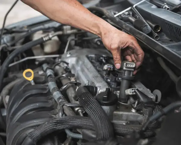 Mechanik wymienia cewkę zapłonową, co może być rozwiązaniem problemów z nierówną pracą silnika.