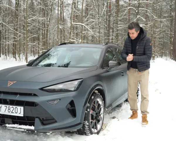 Mężczyzna obok matowego, szarego Formentor Cupra w zimowym lesie.
