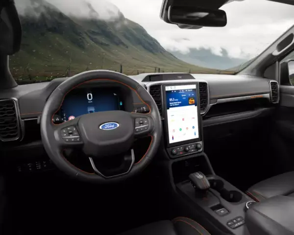 Wnętrze nowoczesnego Ford SUV z dużym ekranem dotykowym i cyfrowymi zegarami. Widok na górzysty krajobraz przez przednią szybę.