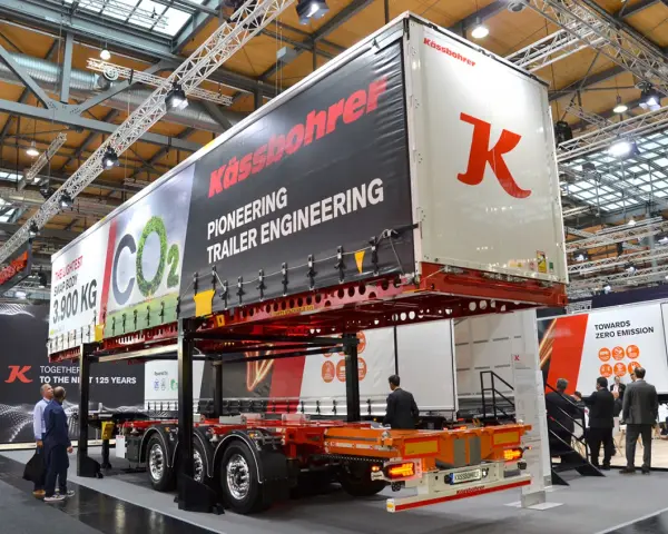 Nowa naczepa Kässbohrer z napisem "Pioneering Trailer Engineering". W tle ludzie zwiedzają targi.