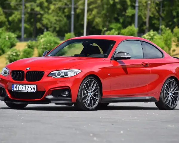 Czerwone BMW f23 coupe z czarnymi dodatkami i felgami stoi na asfalcie.