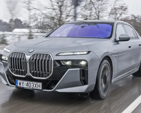 Szary BMW Serii 7 w ruchu, z widocznym grillem i reflektorami. Sprawdź aktualną bmw 7 cena.