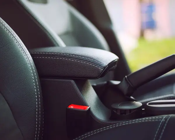 Wnętrze samochodu: czarna skórzana tapicerka, podłokietnik, hamulec ręczny i przycisk auto hold.
